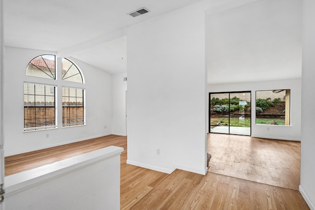 empty room with vaulted ceiling with beams, baseboards, visible vents, and light wood-style floors