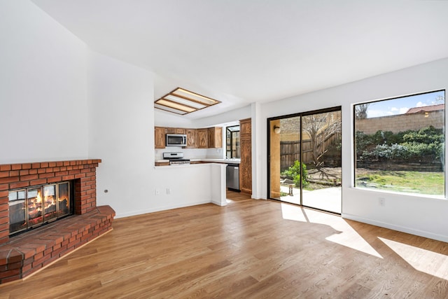 unfurnished living room with light wood-type flooring, a fireplace, and baseboards