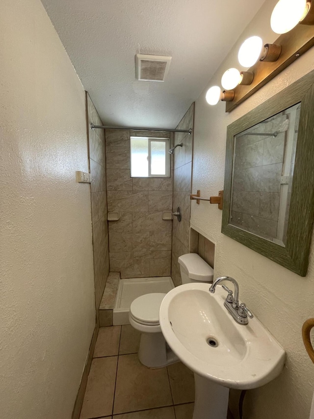 2010 W Lumber St, Lancaster, CA 93536 - full bath featuring toilet, tile patterned floors, a tile shower, a sink, and a textured wall