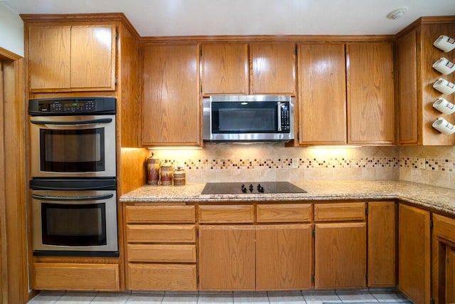 21561 Sheridan Ct, California City, CA 93505 - kitchen with brown cabinetry, tasteful backsplash, light stone countertops, light tile patterned floors, and stainless steel appliances