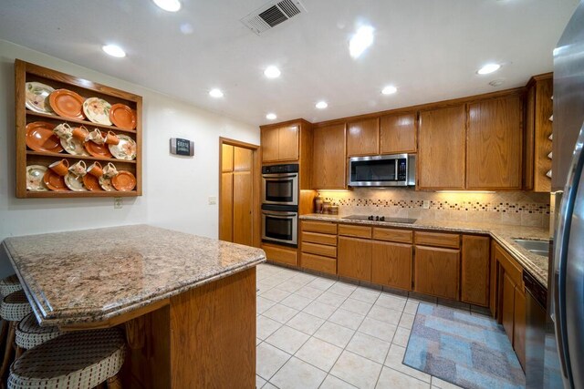 21561 Sheridan Ct, California City, CA 93505 - kitchen with brown cabinetry, visible vents, tasteful backsplash, light tile patterned floors, and stainless steel appliances