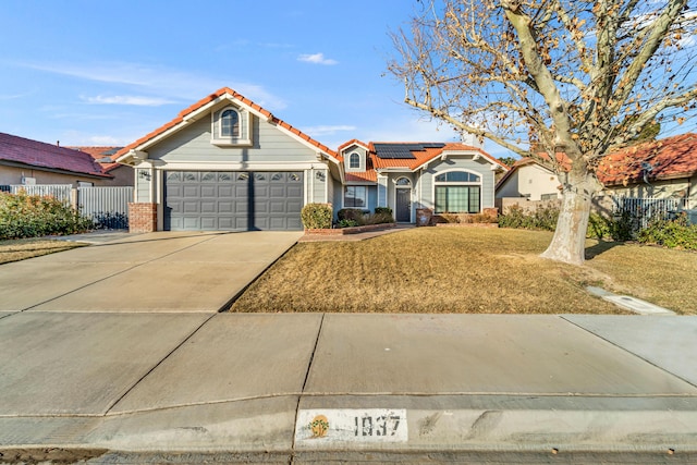 view of front of property featuring a front lawn, solar panels, and a garage