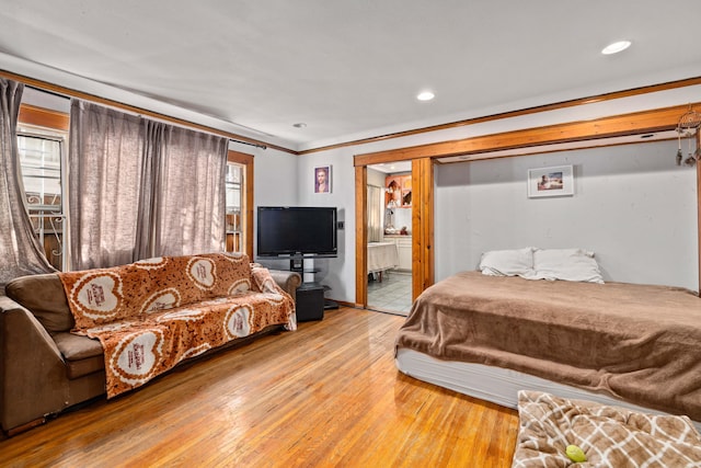 bedroom with connected bathroom, light hardwood / wood-style floors, and ornamental molding