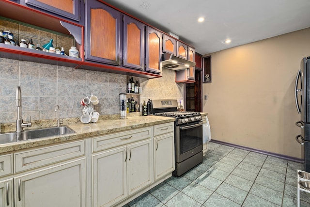 kitchen featuring stainless steel gas range oven, decorative backsplash, sink, and cream cabinetry