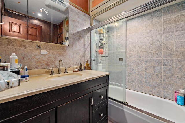 bathroom with combined bath / shower with glass door, decorative backsplash, vanity, and tile walls