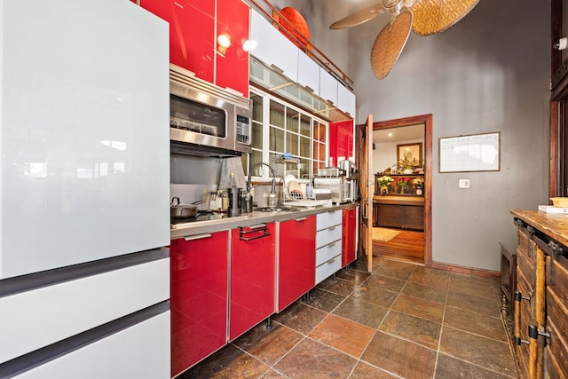 kitchen featuring a high ceiling, white fridge, ceiling fan, and sink