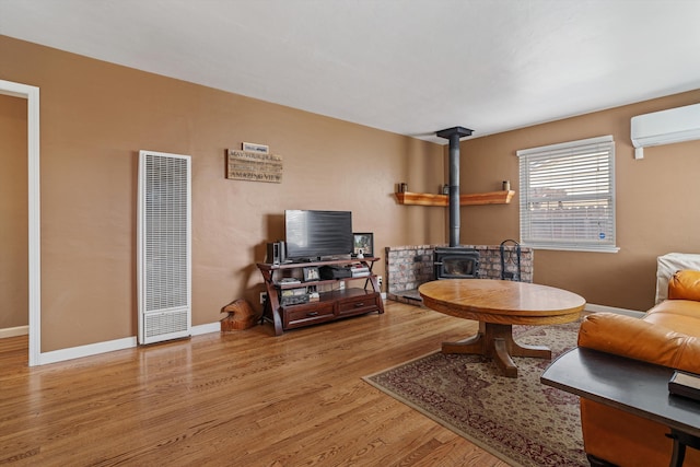 206 Brentwood Dr, Tehachapi, CA 93561 - living room with a wood stove, a heating unit, baseboards, an AC wall unit, and wood finished floors