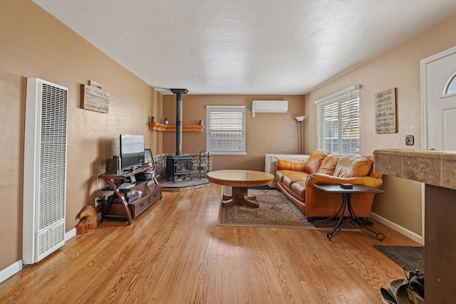 206 Brentwood Dr, Tehachapi, CA 93561 - living room featuring a heating unit, a wall unit AC, a wood stove, baseboards, and wood finished floors