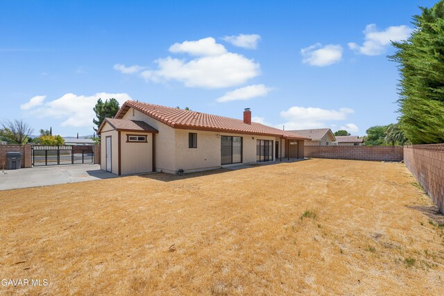 2613 W W Ave K4, Lancaster, CA 93536 - back of property featuring a chimney, a fenced backyard, a gate, stucco siding, and a tile roof