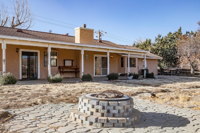 rear view of property featuring a fire pit and a patio area