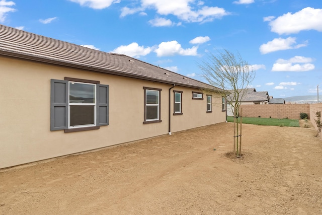 back of property featuring fence and stucco siding