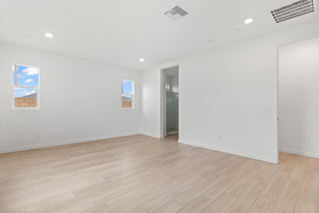 empty room featuring light wood finished floors, visible vents, plenty of natural light, and recessed lighting