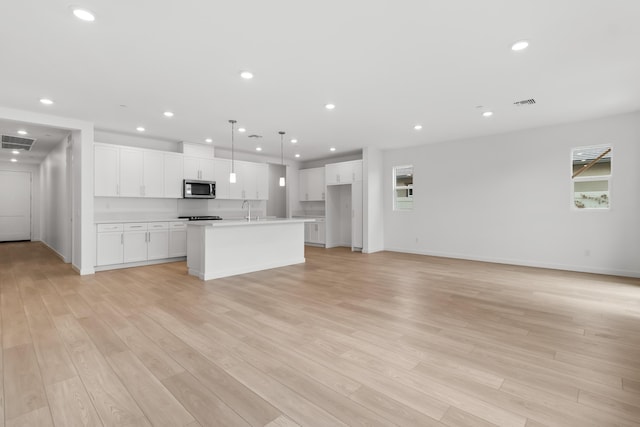 kitchen with recessed lighting, stainless steel microwave, visible vents, and light wood finished floors