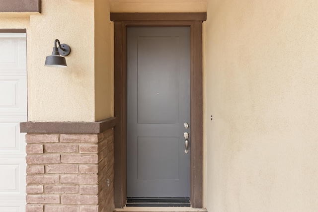 view of exterior entry featuring a garage and stucco siding