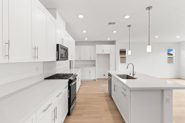 kitchen with a sink, recessed lighting, stainless steel appliances, white cabinets, and light wood finished floors