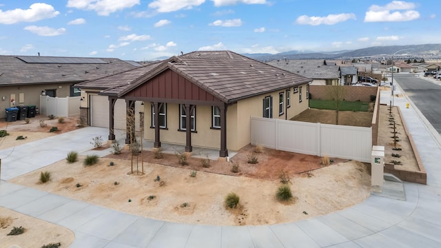 exterior space with fence, covered porch, stucco siding, concrete driveway, and a mountain view