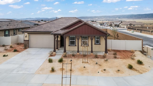 view of front of home with a mountain view, a porch, concrete driveway, and fence