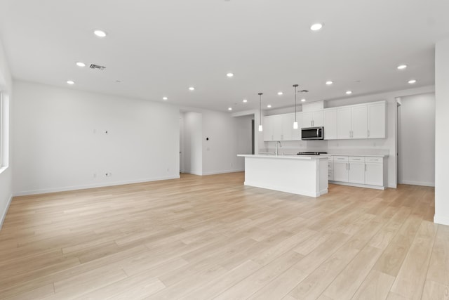 kitchen featuring recessed lighting, stainless steel microwave, visible vents, and open floor plan