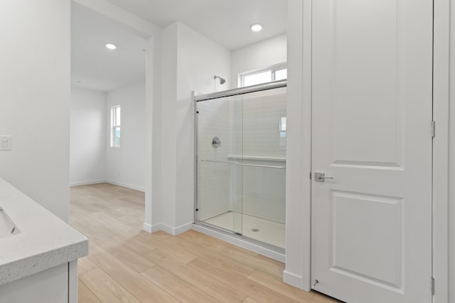 full bath with wood finished floors, a stall shower, a wealth of natural light, and baseboards