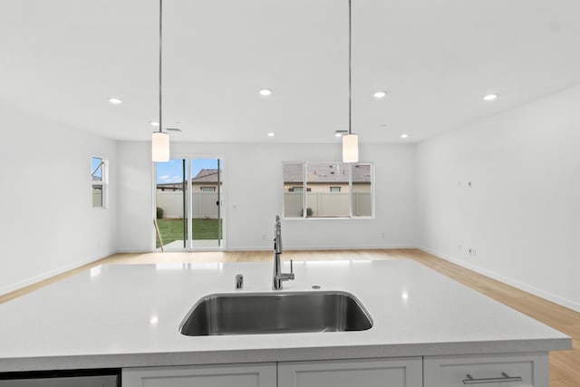 kitchen featuring decorative light fixtures, open floor plan, recessed lighting, and a sink