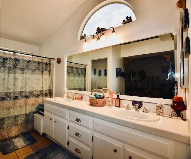 bathroom featuring vaulted ceiling, double vanity, tile patterned flooring, and a sink