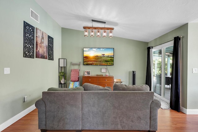 living room featuring a textured ceiling, lofted ceiling, and hardwood / wood-style flooring