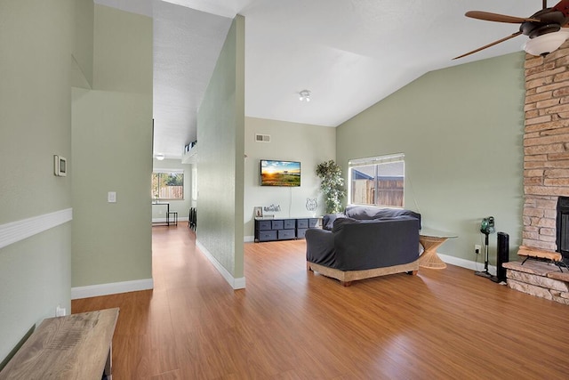 living room with a fireplace, light hardwood / wood-style flooring, vaulted ceiling, and ceiling fan