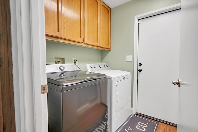 laundry area featuring separate washer and dryer, hardwood / wood-style floors, and cabinets