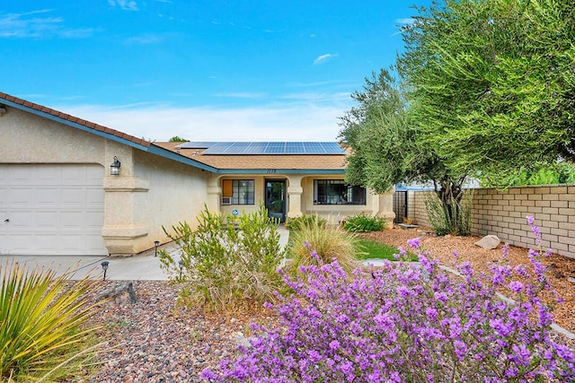 single story home with a garage and solar panels