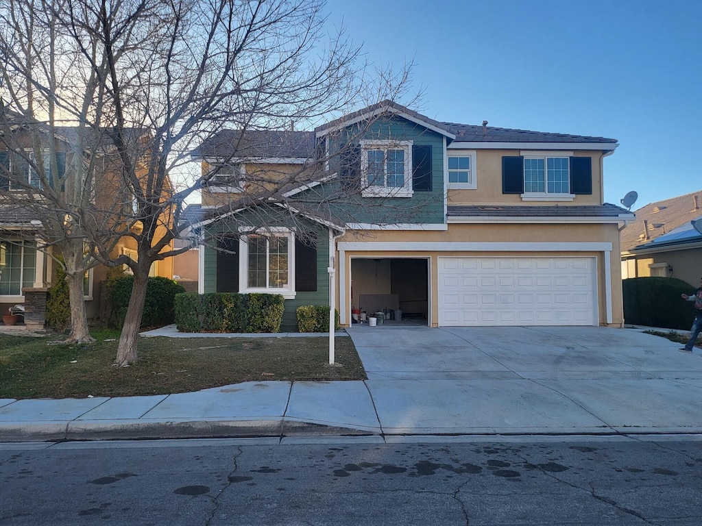 traditional-style home featuring driveway, an attached garage, and stucco siding