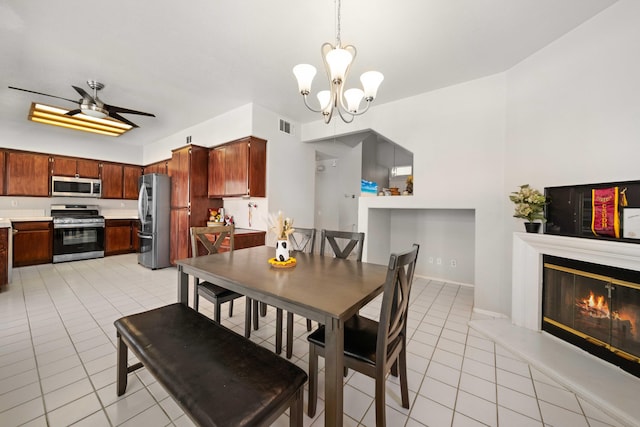 36933 Cadmia Ct, Palmdale, CA 93552 - dining space featuring light tile patterned floors, a glass covered fireplace, a chandelier, and ceiling fan