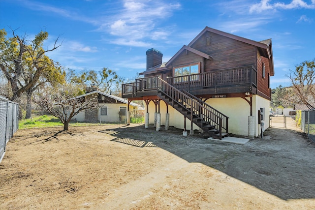 rear view of house with stairs, a gate, fence, a wooden deck, and stucco siding