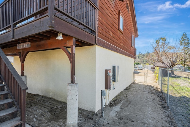 view of home's exterior featuring stairway, fence, a gate, and stucco siding