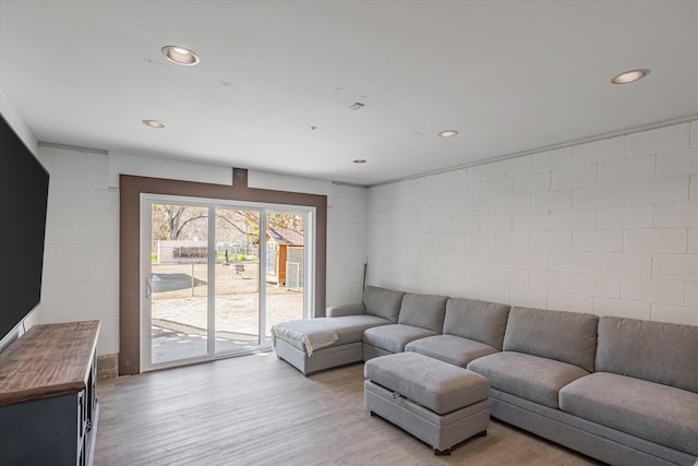 living area with light wood-style floors, recessed lighting, and concrete block wall