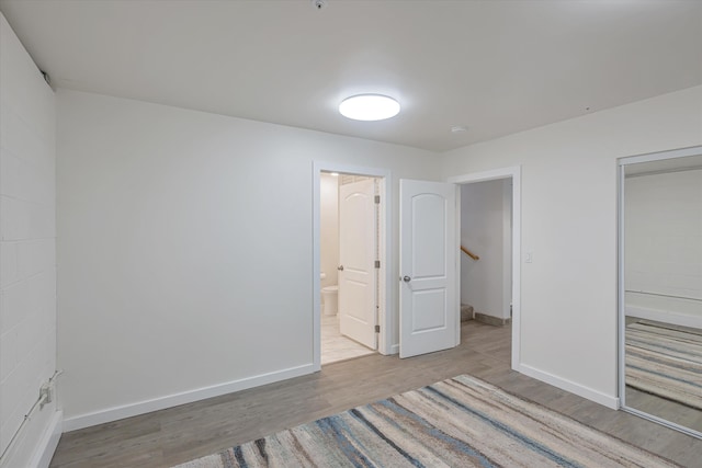 unfurnished bedroom featuring a closet, baseboards, and wood finished floors