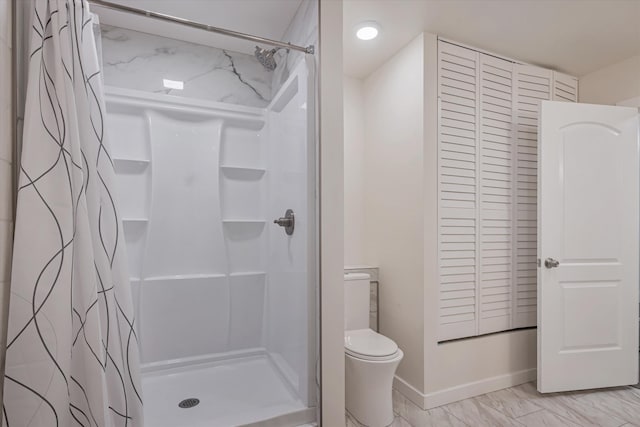 bathroom with a closet, a shower stall, and toilet