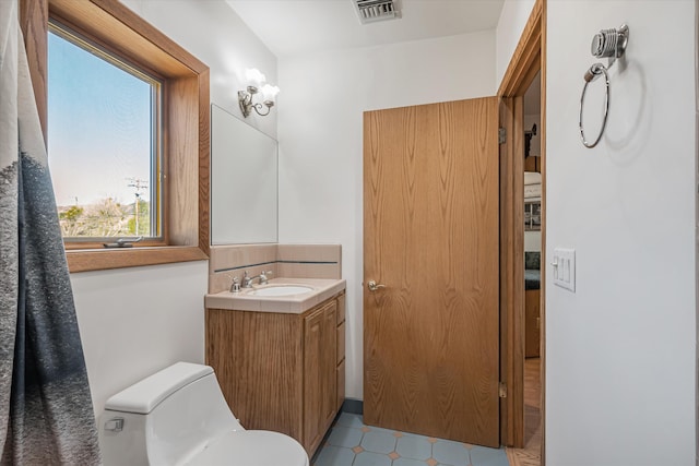 bathroom with toilet, visible vents, and vanity