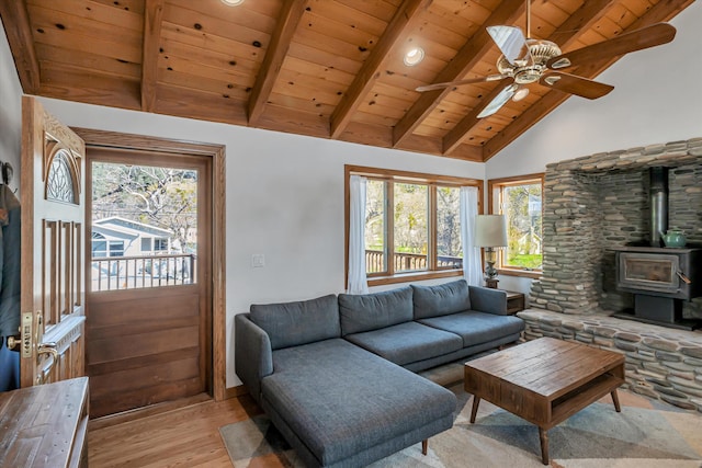 living area featuring beam ceiling, a ceiling fan, a wood stove, light wood-type flooring, and wooden ceiling