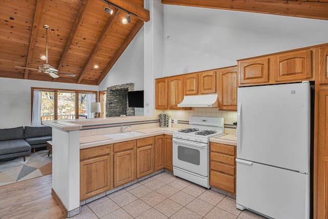 kitchen featuring tile counters, open floor plan, a sink, white appliances, and under cabinet range hood