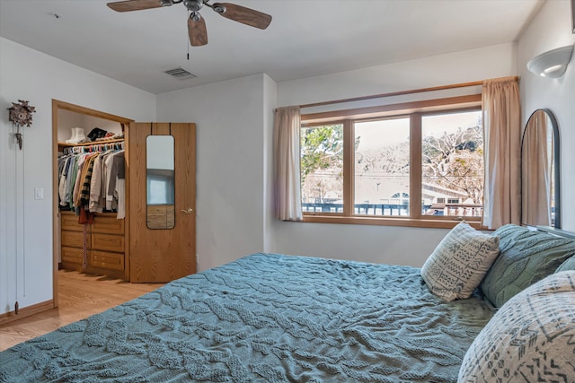 bedroom featuring a closet, visible vents, a spacious closet, a ceiling fan, and wood finished floors