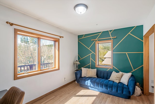 living area with plenty of natural light, baseboards, and wood finished floors