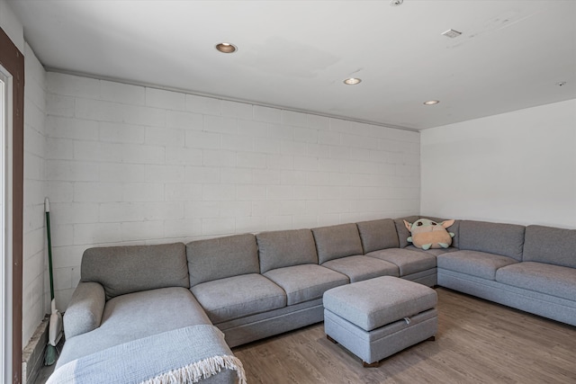 living area featuring wood finished floors, concrete block wall, and recessed lighting