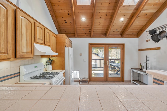 kitchen with white appliances, tile countertops, french doors, under cabinet range hood, and backsplash