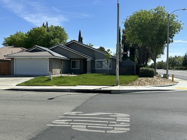 view of front facade with fence, an attached garage, driveway, stucco siding, and a front lawn