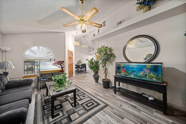 living room featuring hardwood / wood-style floors, a textured ceiling, high vaulted ceiling, and ceiling fan