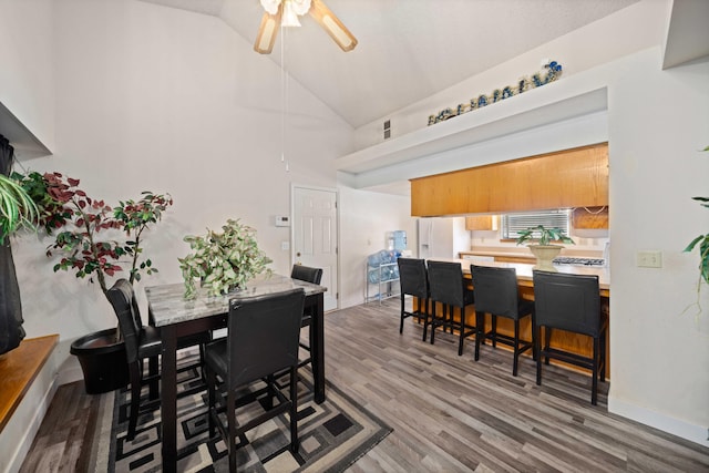 dining area with hardwood / wood-style floors, high vaulted ceiling, and ceiling fan