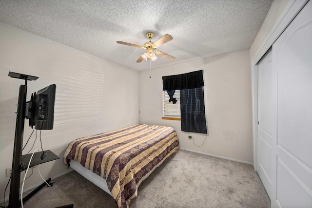 carpeted bedroom with ceiling fan, a closet, and a textured ceiling