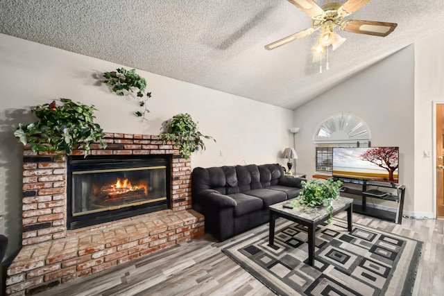 living room featuring a fireplace, a textured ceiling, hardwood / wood-style flooring, and vaulted ceiling