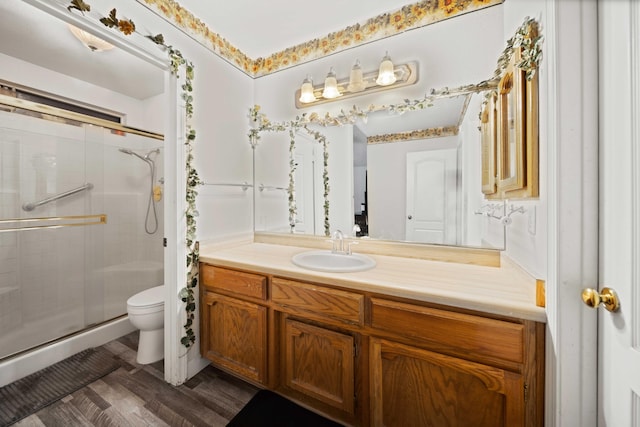 bathroom featuring toilet, vanity, a shower with shower door, and hardwood / wood-style flooring