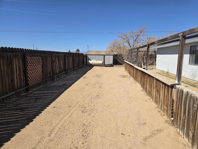 view of yard featuring a storage shed, an outdoor structure, and a fenced backyard